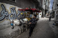 A Palestinian boy sells bananas on a donkey carte in an alley in the Shati refugee camp, in Gaza City, Wednesday, Nov. 25, 2020. Israel's blockade of the Hamas-ruled Gaza Strip has cost the seaside territory as much as $16.7 billion in economic losses and caused its poverty and unemployment rates to skyrocket, a U.N. report said Wednesday, as it called on Israel to lift the 13-year closure. (AP Photo/Khalil Hamra)