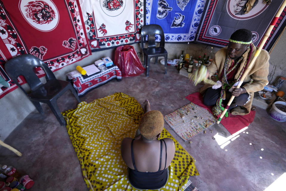 Un curandero tradicional, Shadrack Mashabane, consulta a su esposa antes de hacerle una prueba del VIH, en Bushbuckridge, Sudáfrica, el 9 de mayo de 2024. (AP Foto/Themba Hadebe)