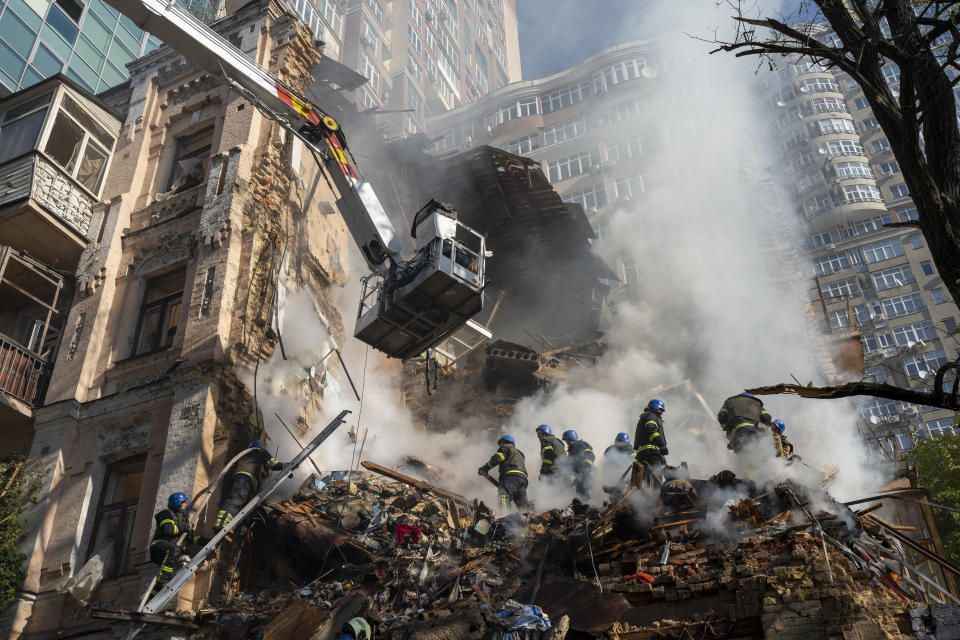 Firefighters work after a drone attack on buildings in Kyiv, Ukraine, Monday, Oct. 17, 2022. Waves of explosive-laden suicide drones struck Ukraine's capital as families were preparing to start their week early Monday, the blasts echoing across Kyiv, setting buildings ablaze and sending people scurrying to shelters. (AP Photo/Roman Hrytsyna)