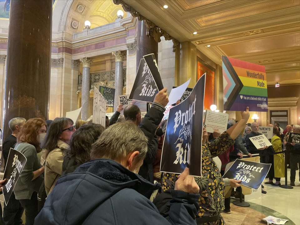 Protesters hold signs as they chant for and against a bill that would make Minnesota a trans refuge state, and strengthen protections for kids and their families who come to the state for gender-affirming care, outside the room where lawmakers would vote on the bill at the state capitol, Thursday, March 23, 2023, in St. Paul, Minn. (AP Photo/Trisha Ahmed)