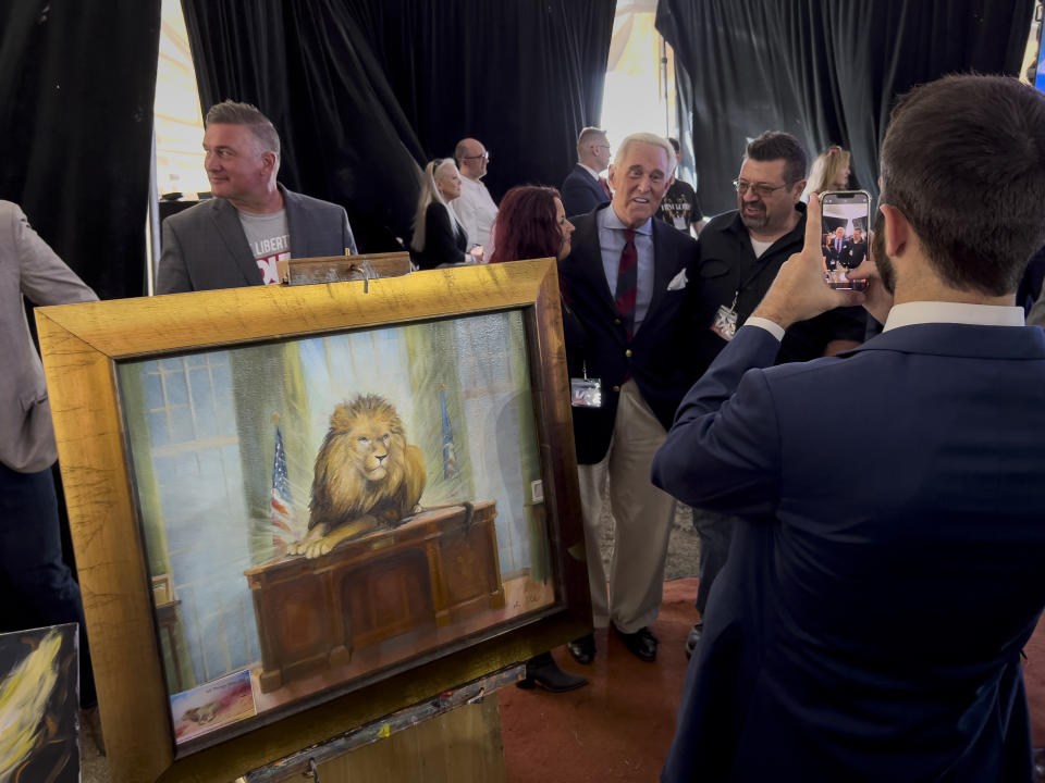 FILE - Roger Stone poses for photographs as a painting by Elisabeth Miller, titled "Lion of Judah on the Resolute Desk," is displayed during the ReAwaken America Tour at Cornerstone Church in Batavia, N.Y., Aug. 12, 2022. (AP Photo/Carolyn Kaster, File)