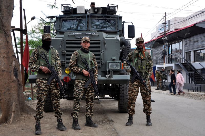 FILE PHOTO: Security personnel stand guard in front of their armoured vehicle outside a polling station, in Imphal