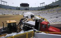 A tractor dumps snow into the back of a truck after it was cleared from the bleachers by paid volunteers at Lambeau Field in Green Bay, Wisconsin, the home field of the Green Bay Packers of the National Football League (NFL), December 21, 2013. In winter months, the team calls on the help of hundreds of citizens, who also get paid a $10 per-hour wage, to shovel snow and ice from the seating area ahead of games, local media reported. The Packers will host the Pittsburgh Steelers on Sunday, December 22. REUTERS/Mark Kauzlarich (UNITED STATES - Tags: ENVIRONMENT SPORT FOOTBALL)