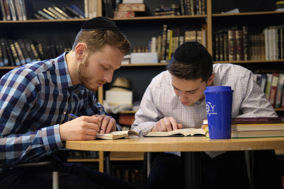 Yeshiva University students Aaron Heideman, left, and Marc Shapiro study in the university's library in New York, Thursday, Dec. 12, 2019. They praised President Donald Trump's executive order to expand the scope of potential anti-Semitism complaints on U.S. college campuses. They said they worry that friends attending other universities might be targeted by anti-Semitic attacks and that this could help protect them. (AP Photo/Luis Andres Henao)