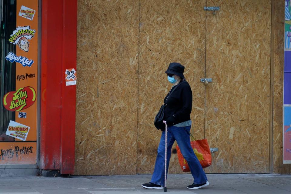 A shopper passes a boarded up shop on Oxford Street in London: AP