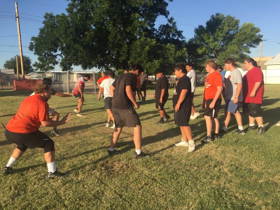 Offensive and defensive linemen from Artesia High School go through summer football practice drills on July 19, 2023.