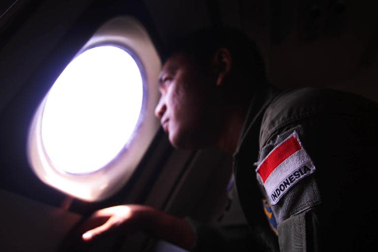 An Indonesian Navy search and rescue personel looks out from an aircraft window during a search for the missing Malaysia Airlines flight MH370 in the waters bordering Indonesia, Malaysia and Thailand on March 10, 2014
