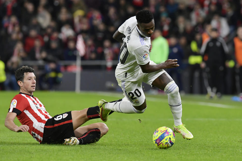 Real Madrid's Vinicius Junior, right, and Athletic Bilbao's Mikel Vesga challenge for the ball during the Spanish La Liga soccer match between Athletic Club Bilbao and Real Madrid at the San Mames stadium in Bilbao, Spain, Sunday, Jan. 22, 2023. (AP Photo/Alvaro Barrientos)