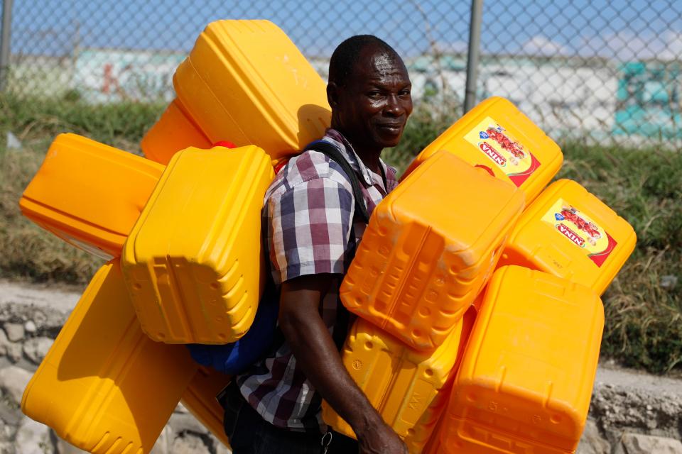 A vendor carries empty containers for fuel in Port-au-Prince, Haiti, Wednesday, March 6, 2024. (AP Photo/Odelyn Joseph)