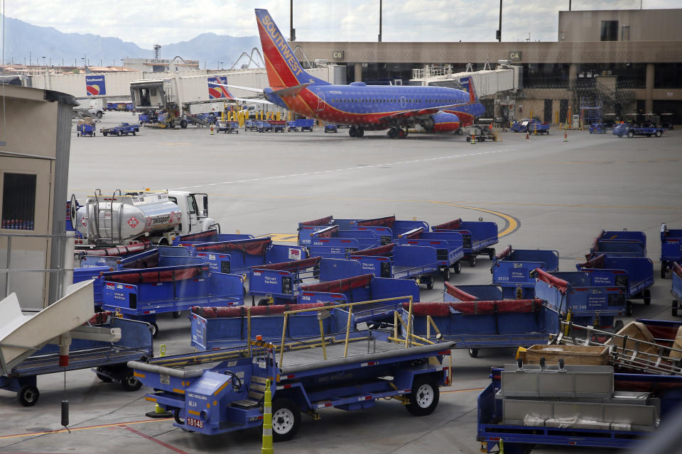 Empty luggage carts sit on the tarmac along with a Southwest Airlines plane at Sky Harbor Airport, Tuesday, March 17, 2020, in Phoenix, as airlines cut flights due to the coronavirus outbreak. (AP Photo/Sue Ogrocki)