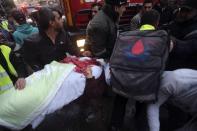 Civil defence personnel help a wounded woman at the site of an explosion in Beirut's southern suburbs January 2, 2014. The powerful explosion in Shi'ite group Hezbollah's southern Beirut stronghold killed three people on Thursday and sent a column of smoke into the sky, a witness said. (REUTERS/Hasan Shaaban)