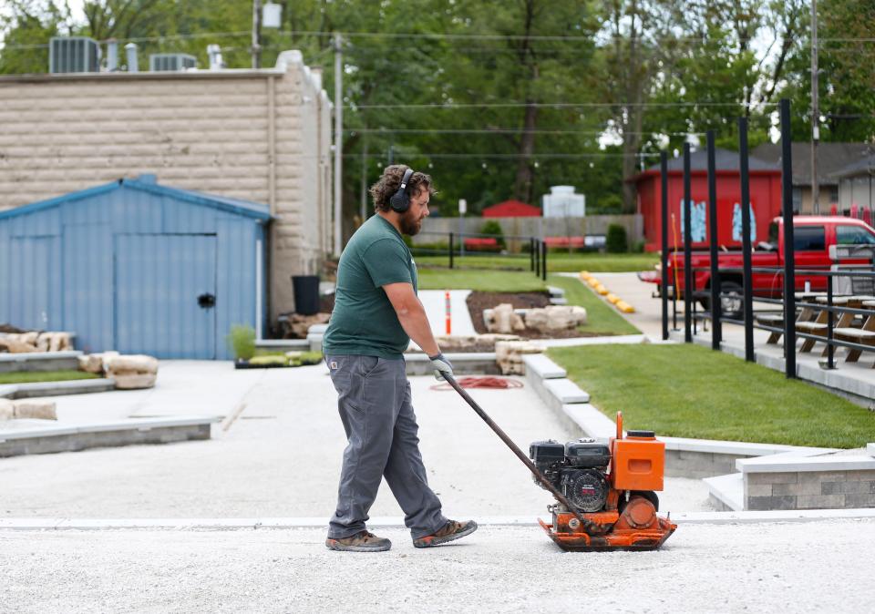 Michael Spyres operates a compacting machine as he works on the new patio area of Tie & Timber Beer Co. on Friday, May 8, 2020. Spyres, who works as an opera singer, had his gig work disappear when the pandemic hit so he took temporary work doing construction and landscaping.