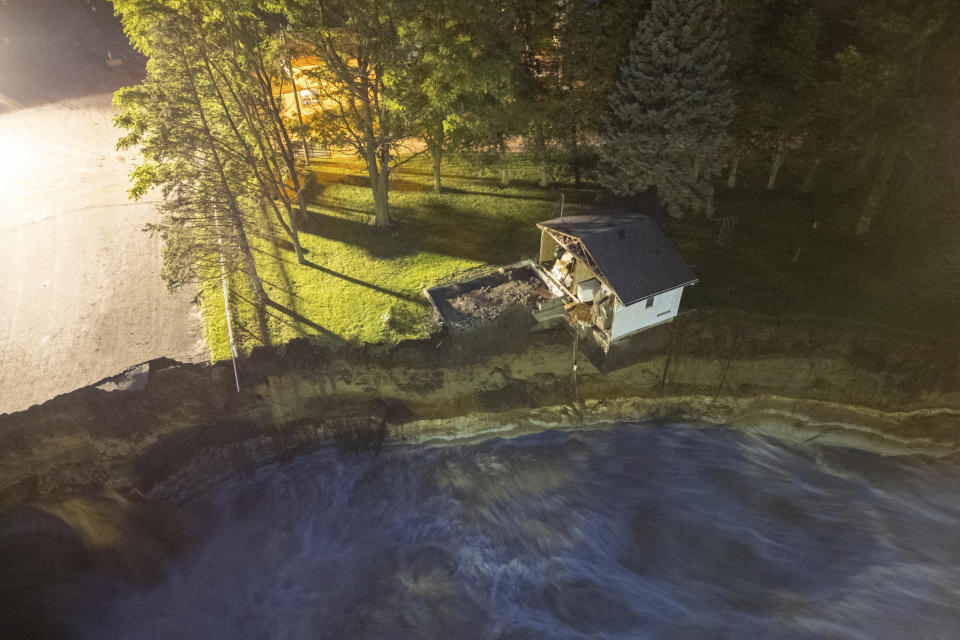 This long-exposure drone photo provided by AW Aerial shows a home as it teeters before partially collapsing into the Blue Earth River at the Rapidan Dam in Rapidan, Minn., Tuesday, June 25, 2024. (Andrew Weinzierl/AW Aerial via AP)