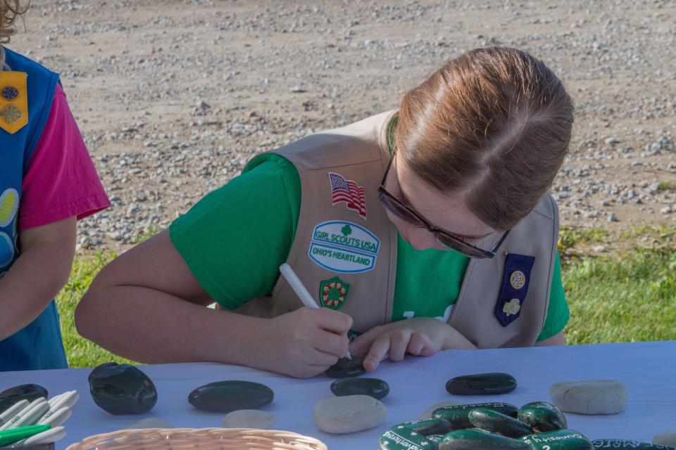 Sheridan Deem, a Girl Scout from Troop 5949A, writes on a rock at the Tuesday groundbreaking celebration for the Girl Scouts of Ohio's Heartland's new STEM Leadership Center & Maker Space in Galloway. The rock painting was an opportunity for people to write words of inspiration that will be placed in the new building.