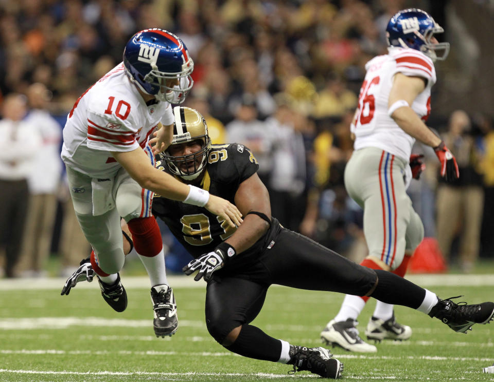 NEW ORLEANS, LA - NOVEMBER 28: Quarterback Eli Manning #10 of the New York Giants throws the ball as he is hit by Will Smith #91 of the New Orleans Saints in the first half at Mercedes-Benz Superdome on November 28, 2011 in New Orleans, Louisiana. (Photo by Ronald Martinez/Getty Images)