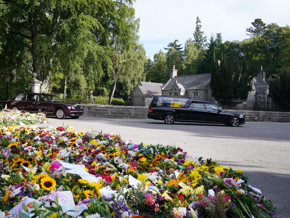 Flowers left for the Queen lined the gates of Balmoral as the hearse drove away.