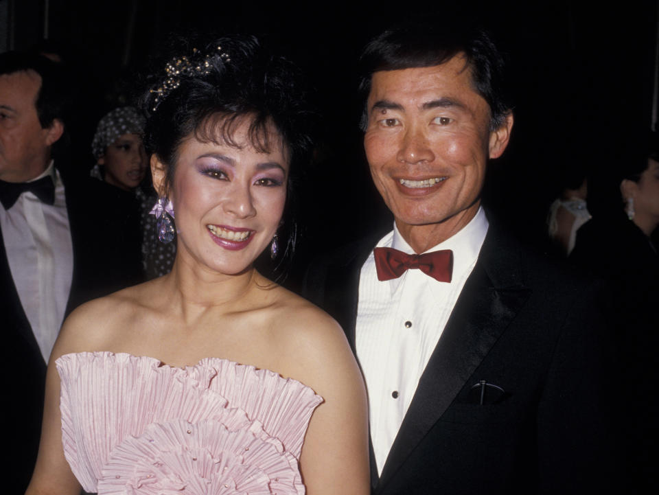 Two individuals in formal attire smiling for the camera at an event