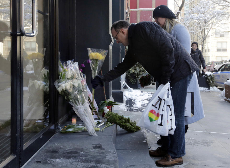 A couple adds to the flowers placed outside the apartment building of actor Phillip Seymour Hoffman, in New York, Tuesday, Feb. 4, 2014. Autopsy results are expected soon in the death of actor Phillip Seymour Hoffman but police say it may take longer to determine if the heroin found in his apartment contains additives designed intensify the high. (AP Photo/Richard Drew)