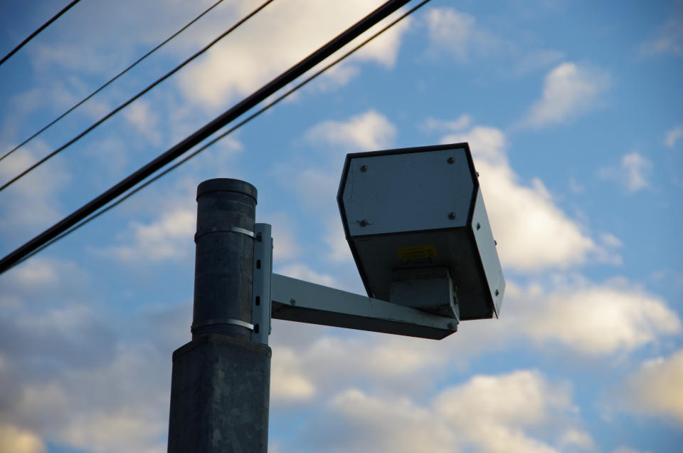 Fixed speed camera on road.