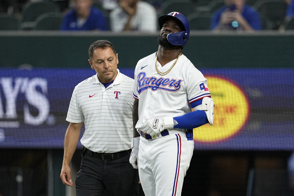 Texas Rangers head athletic trainer Matt Lucero, left, attends to Adolis Garcia, right, after Garcia was hit by a pitch in the eighth inning of a baseball game against the Tampa Bay Rays, Wednesday, July 19, 2023, in Arlington, Texas. Garcia left the game with an unknown left arm injury. (AP Photo/Tony Gutierrez)