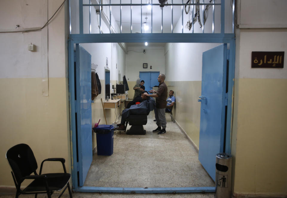 CAPTION ADDITION: ADDS DETAILS ABOUT WHICH PRISON HAD RIOTS: FILE - In this April 3, 2018, file photo, prisoners cut the hair of other inmates in the barber shop of a Kurdish-run prison housing former members of the Islamic State group, in Qamishli, north Syria. A spokesman for Kurdish-led forces in northeastern Syria said Monday, March. 30, 2020 they have put an end to riots by Islamic State militants in a prison there. The riots broke out late on Sunday in a prison in the town of Hassakeh and lasted several hours. Kurdish authorities run more than two dozen detention facilities scattered around northeastern Syria, holding about 10,000 IS fighters. (AP Photo/Hussein Malla, File)