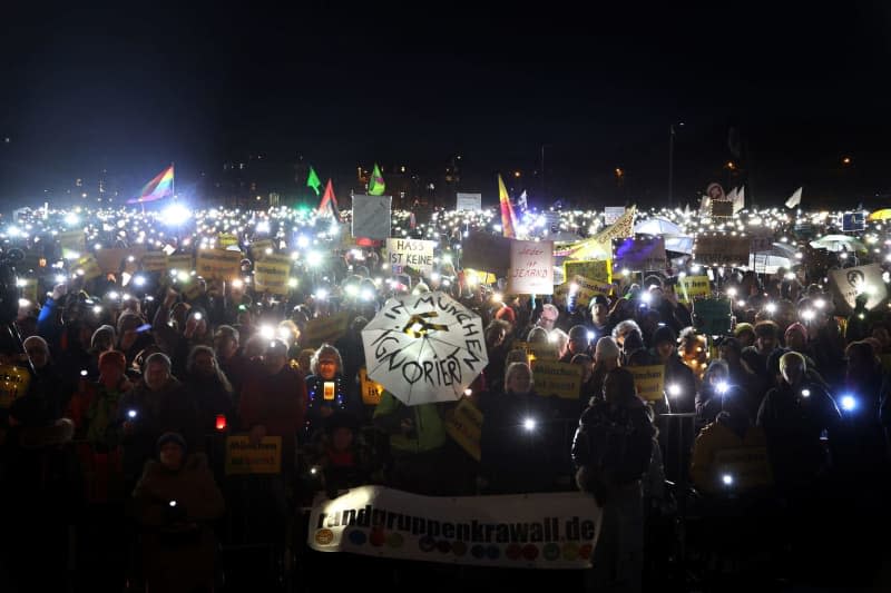 People stand at the Theresienwiese during a demonstration under the motto "Sea of lights for democracy, against racism, anti-Semitism and hate speech". Karl-Josef Hildenbrand/dpa