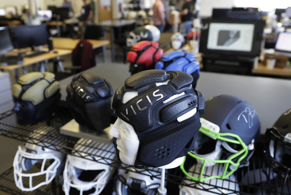 This photo taken May 23, 2019, shows helmets on a rack at the Seattle headquarters of football helmet maker VICIS. The company's latest offering is the ULTIM cap, which is intended for use with youth flag football and competitive 7-on-7 football played during the offseason for youth and high school programs. (AP Photo/Ted S. Warren)