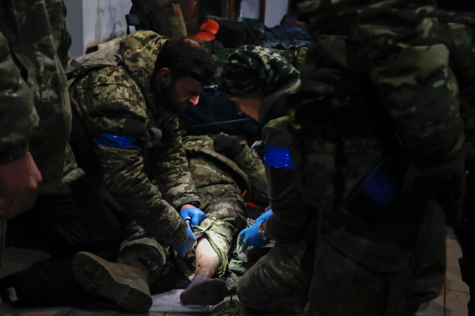 Ukrainian servicemen administer first aid to a wounded soldier in a shelter in Soledar (AP)