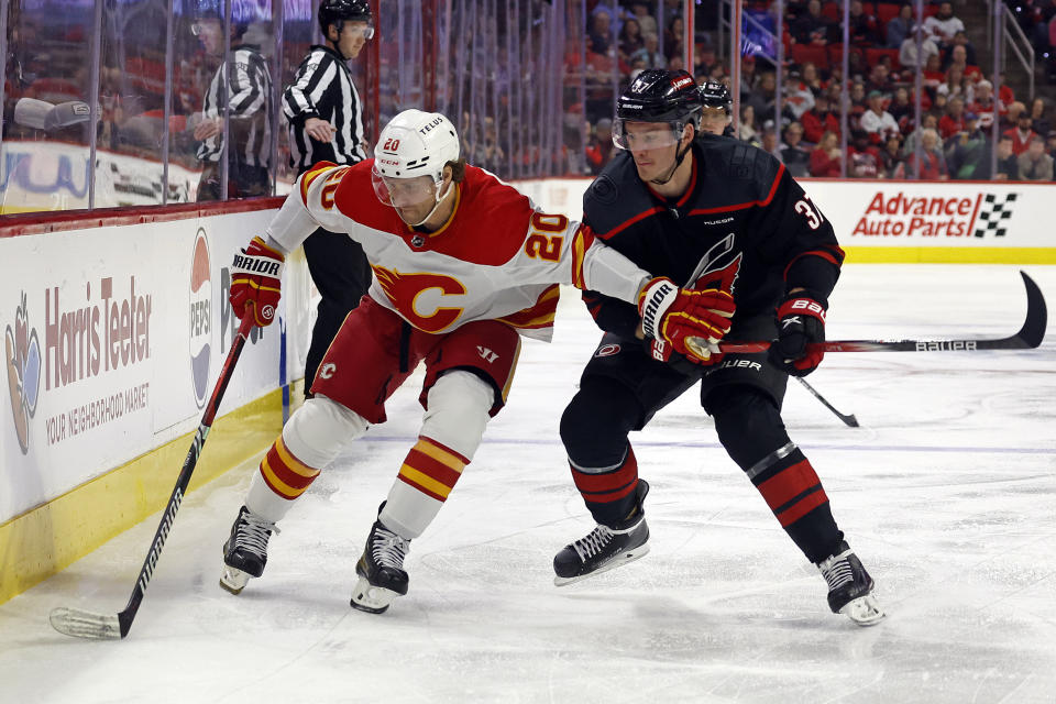 Calgary Flames' Blake Coleman (20) protects the puck from Carolina Hurricanes' Andrei Svechnikov (37) during the first period of an NHL hockey game in Raleigh, N.C., Sunday, March 10, 2024. (AP Photo/Karl B DeBlaker)