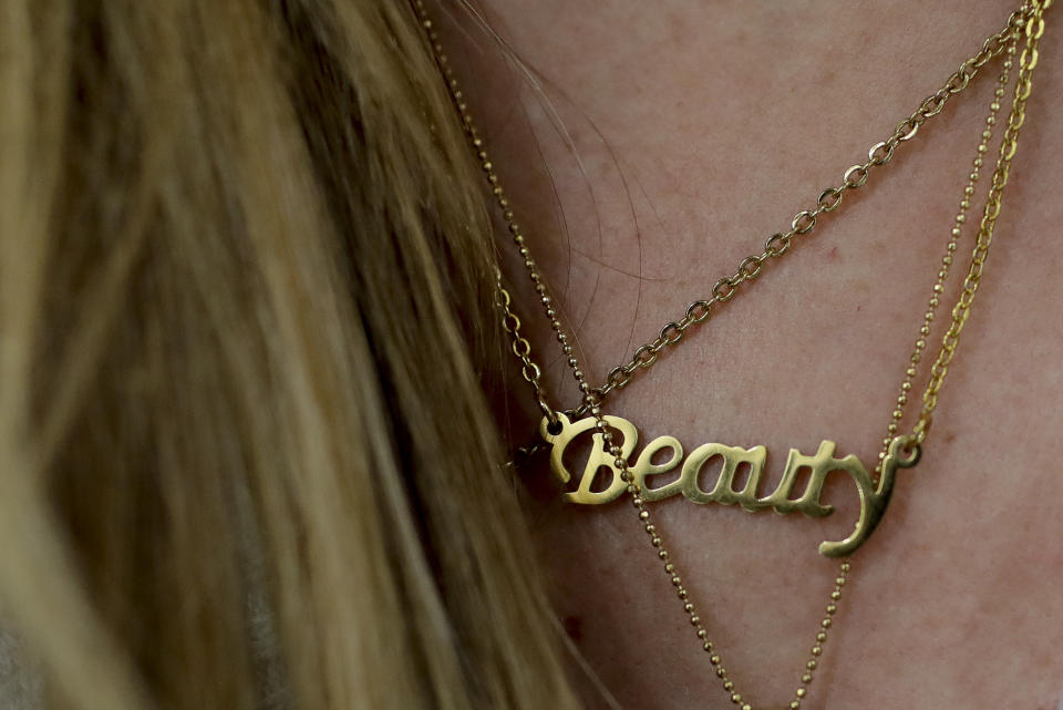 Carolina Dejan wears a neckless featuring the word "Beauty" at a beauty salon where she is getting extensions using real hair from women who sold theirs in Caracas, Venezuela, Thursday, April 4, 2019. In the face of unbridled inflation in the first quarter, sales suffered a brutal contraction, including the beauty industry which fell over 60%, according to economist Luis Vicente León, president of the local polling company Datanálisis. (AP Photo/Natacha Pisarenko)