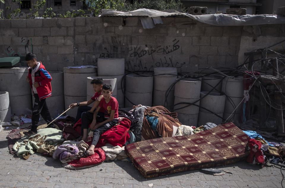 Palestinian children sit among belongings salvaged from the rubble of their destroyed house following early morning Israeli airstrikes, in Gaza City, Monday, May 17, 2021. (AP Photo/Khalil Hamra)