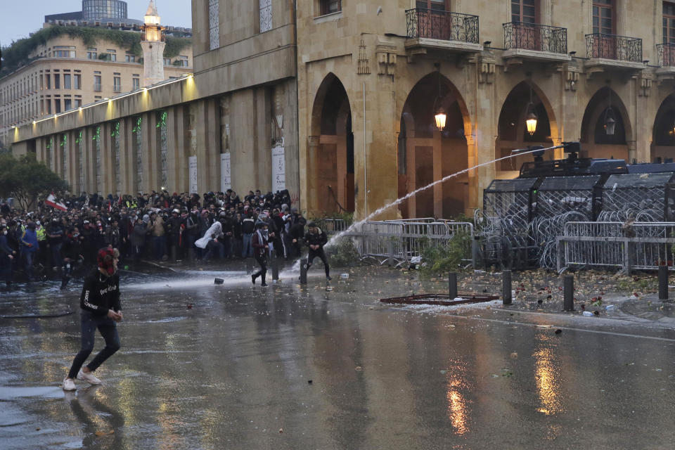 Anti-government demonstrators clash with riot police at a road leading to the parliament building in Beirut, Lebanon, Saturday, Jan. 18, 2020. Riot police fired tears gas and sprayed protesters with water cannons near parliament building to disperse thousands of people after riots broke out during a march against the ruling elite amid a severe economic crisis. (AP Photo/Hassan Ammar