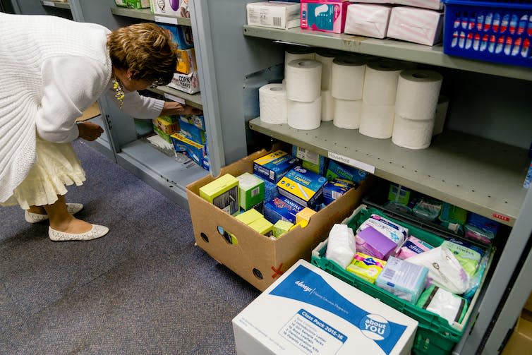 A woman looks at a shelf in a food bank storage room.