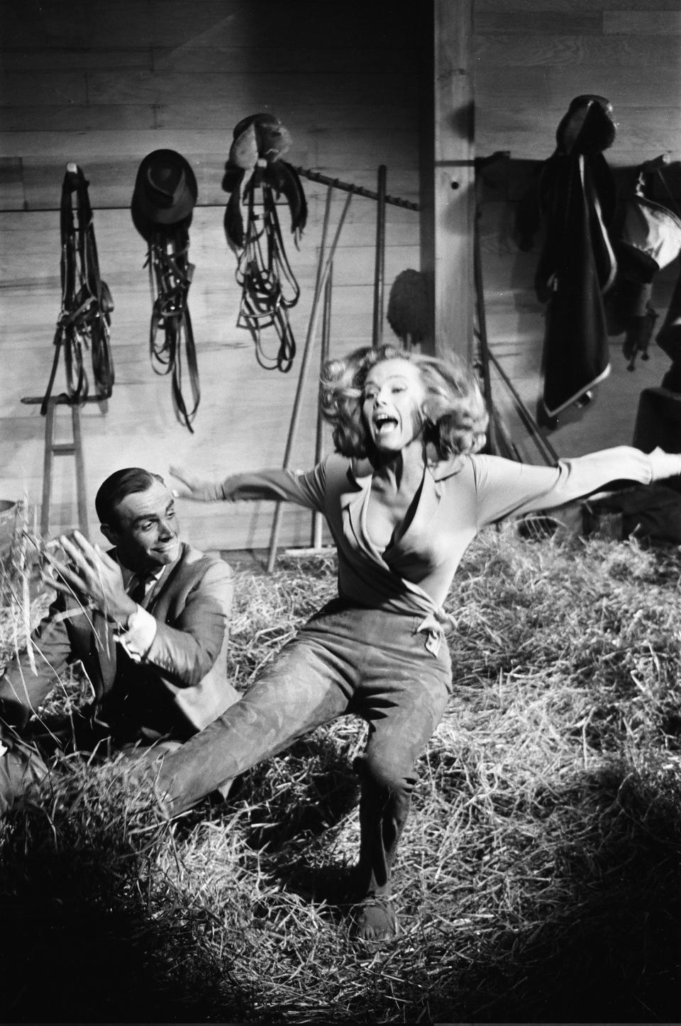 Honor Blackman as Pussy Galore and Sean Connery as James Bond seen here filming a fight scene which develops into a love scene in Goldfingers barn on the Pinewood studios back lot, 2nd June 1964. (Photo by Victor Crawshaw/Mirrorpix/Getty Images)