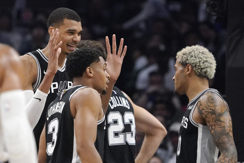 San Antonio Spurs center Victor Wembanyama, left, talks to forward Keldon Johnson, second from left, and forward Jeremy Sochan, right, during the first half of an NBA basketball game Sunday, Oct. 29, 2023, in Los Angeles. (AP Photo/Mark J. Terrill)