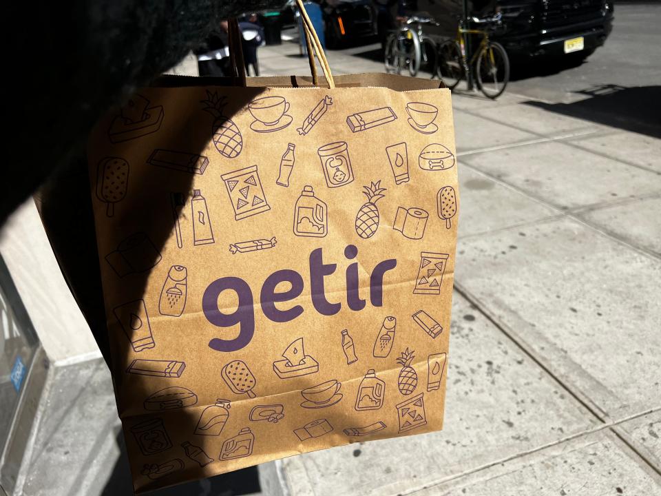 hand holding a getir grocery bag over a sidewalk in new york