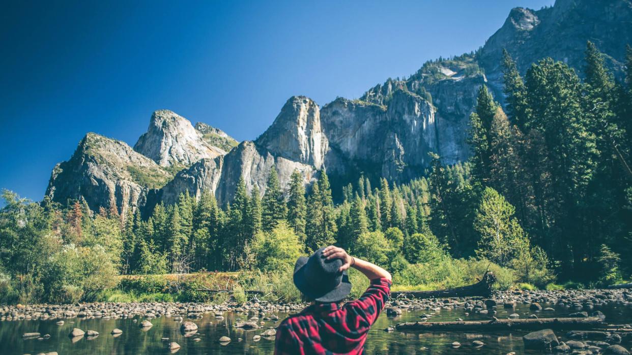 A shot of a young woman walking along a river in a majestic landscape.