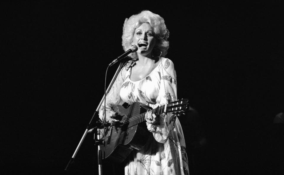A woman playing acoustic guitar and singing onstage