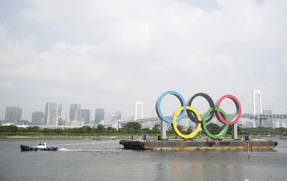 A tugboat moves a symbol installed for the Olympic and Paralympic Games Tokyo 2020 on a barge moved away from its usual spot off the Odaiba Marine Park in Tokyo Thursday, Aug. 6, 2020. The five Olympic rings floating on a barge in Tokyo Bay were removed for what is being called “maintenance,” and officials says they will return to greet next year's Games. The Tokyo Olympics have been postponed for a year because of the coronavirus pandemic and are to open on July 23, 2021. The Paralympics follow on Aug. 24. (AP Photo/Hiro Komae)