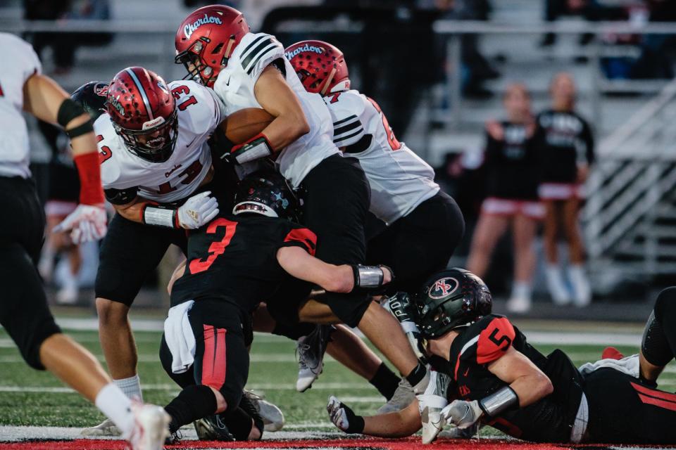 Trevor Bean, left, and Matthew Beach, bottom right, attempt to make a tackle against Chardon, Friday, Oct. 1 at Woody Hayes Quaker Stadium.