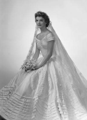 Bridal portrait of Jacqueline Lee Bouvier shows her in an Anne Lowe-designed wedding dress, a bouquet of flowers in her hands, New York, New York, 1953.