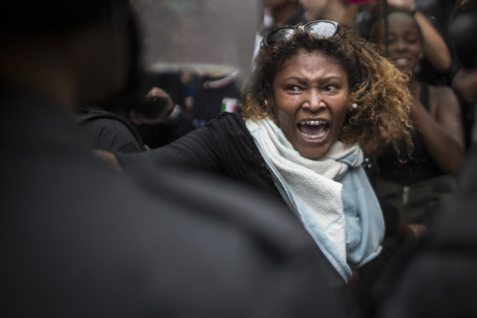 Una mujer grita a los policías mientras vecinos de la favela Pavao-Pavaozinho chocan con la policía antimotines durante una protesta por la muerte de Douglas Rafael da Silva Pereira tras su entierro en Río de Janeiro, Brasil, el jueves 24 de abril de2014. (Foto AP/Felipe Dana)