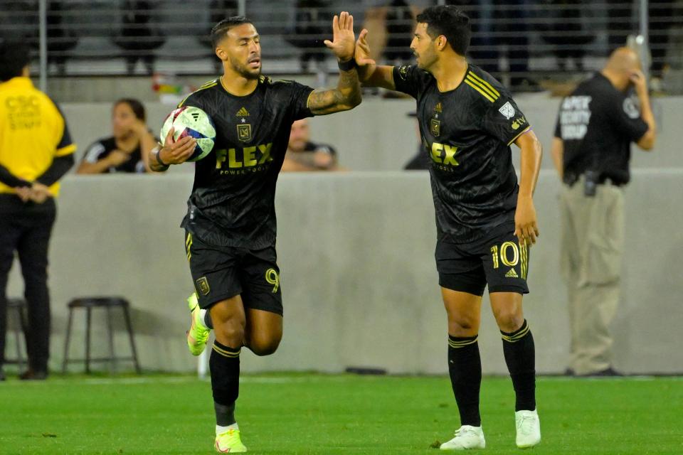 Los Angeles FC forward Denis Bouanga (99) celebrates with teammate Carlos Vela after scoring a goal against the Vancouver Whitecaps at BMO Stadium.