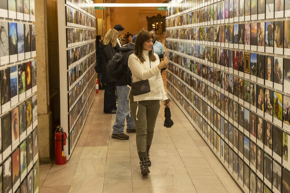 A woman documents the many rows of photos at the Fujifilm Printlife Photo Exhibit. (Photo: Gordon Donovan/Yahoo News)