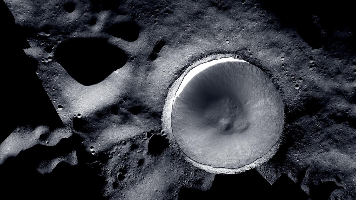  A large crater on the grey, cratered surface of the moon. 