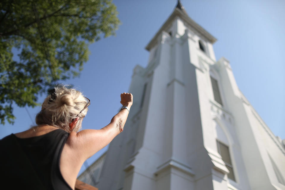CHARLESTON, SC - JUNE 21:  A woman raises her arm in prayer while standing in front of the Emanuel African Methodist Episcopal Church as she listens to a broadcast of the Sunday service taking place after a mass shooting at the church killed nine people on June 21, 2015 in Charleston, South Carolina. Dylann Roof, 21 years old, is suspected of killing the nine people during a prayer meeting in the church, which is one of the nation's oldest black churches in Charleston.  (Photo by Joe Raedle/Getty Images)