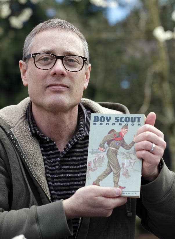 FILE - In this Tuesday, April 1, 2014, file photo, Geoff McGrath displays a vintage Boy Scout Handbook given him as a gift by one of the boys in the Seattle troop he led in Bellevue, Wash. The Boys Scouts of America has revoked the charter of a Seattle church because it allowed a gay adult to continue leading a troop. A Boys Scouts of America attorney told Rainier Beach United Methodist Church last week that it could no longer hosts troops under the Boys Scout name. McGrath, who earned the rank of Eagle Scout, has been leading Seattle Troop 98 since its application was approved last fall. (AP Photo/Elaine Thompson, File)