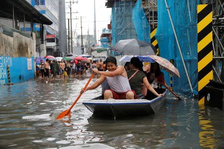 Residents use a makeshift boat to ferry commuters along floodwaters in Quezon City, Metro Manila as a storm sweeps across the main Luzon island, Philippines, September 12, 2017. REUTERS/Dondi Tawatao