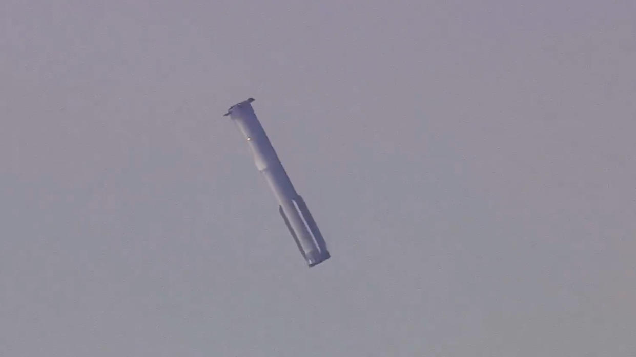  A silver-gray rocket is seen in a gray sky. 