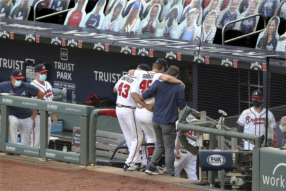 Atlanta Braves manager Brian Snitker and a trainer help pitcher Mike Soroka off the field with an apparent injury, during the third inning of the team's baseball game against the New York Mets, Monday, Aug. 3, 2020, in Atlanta. (Curtis Compton/Atlanta Journal-Constitution via AP)